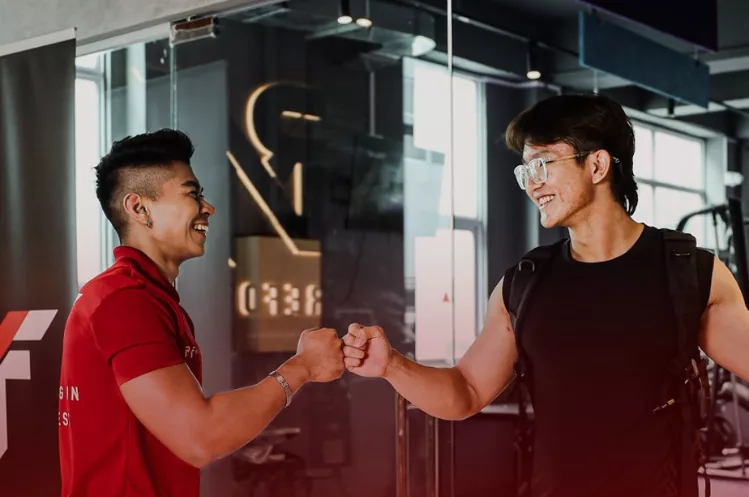 A ReFormd Personal Trainer giving his client a fist bump as they both smile