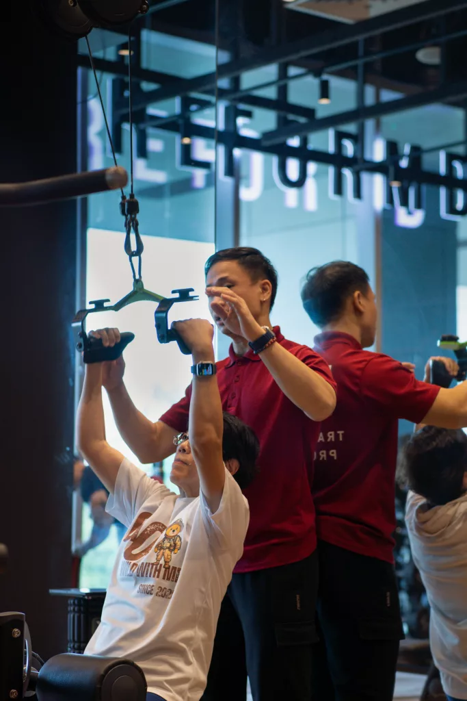 ReFormd Personal Trainer spotting an elderly client on a lat pulldown exercise