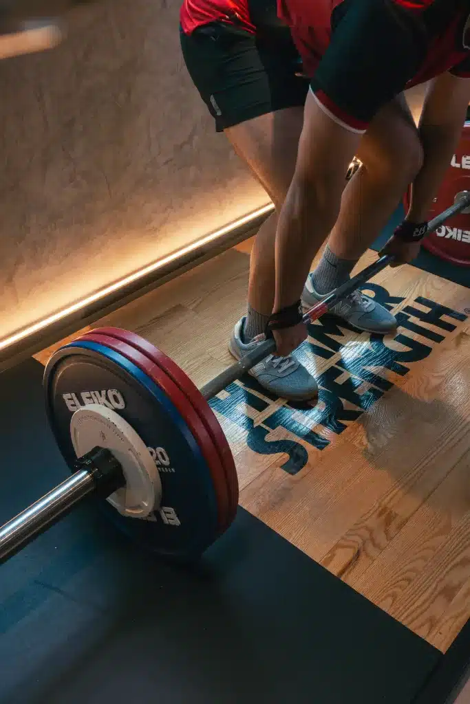 A man deadlifting 170kgs with lifting straps on the bar. The plates are calibrated eleiko plates.